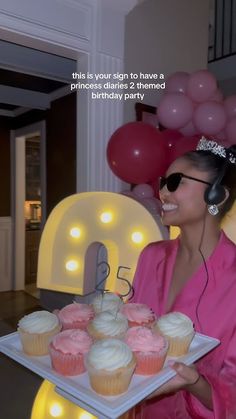 a woman holding a tray with cupcakes on it