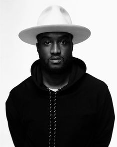 a man wearing a white hat and hoodie poses for a photo in black and white