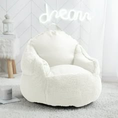 a white chair sitting on top of a rug next to a light that reads dream