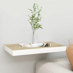 a white table with a vase on it and some books in front of the table