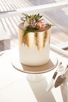 a gold and white wedding cake with succulents