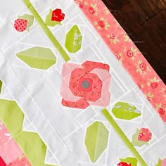 a close up of a quilted table runner with flowers and leaves on the edge