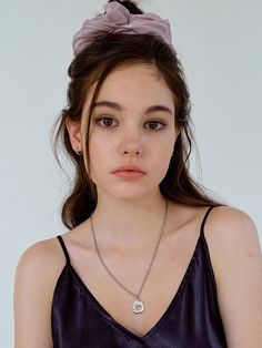 a young woman wearing a purple top and necklace