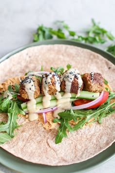 a tortilla filled with meat and veggies on top of lettuce