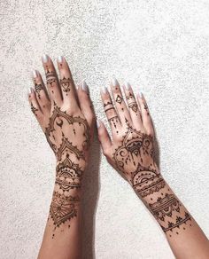 two hands with henna tattoos on them