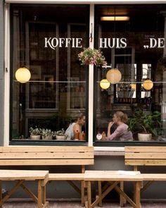 two people sitting at a table in front of a store window