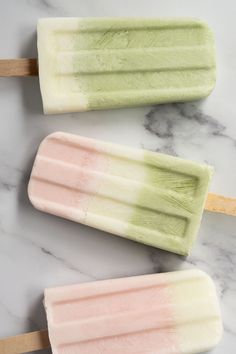 three popsicles sitting on top of a marble counter