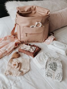 the contents of a diaper bag laid out on top of a bed with blankets