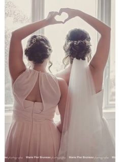 two brides are holding their hands in the shape of a heart