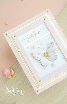 a pink and gold card with a butterfly on it