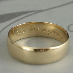 a gold wedding ring with the words, i love you