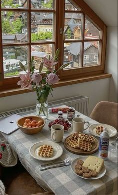 a table topped with waffles and fruit next to a window