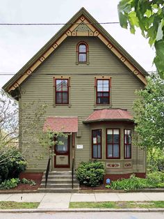 a green house with red trim on the front door and stairs leading up to it