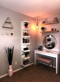 a room with a desk, mirror and shelves on the wall next to a potted plant