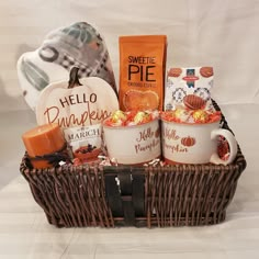 a wicker basket filled with coffee, candy and candies next to pumpkins