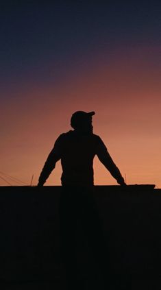 a man standing on top of a roof at sunset