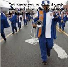 a man in blue and white is marching down the street with an orange and white band