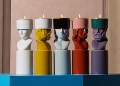 five different colored candles in the shape of people's heads with faces on them