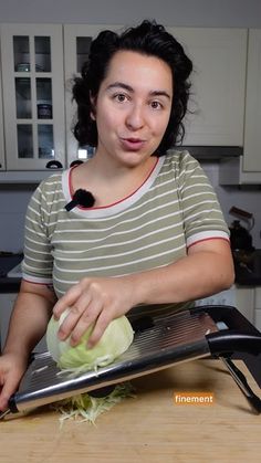 a woman holding a knife and cutting an onion on top of a cutting board in a kitchen