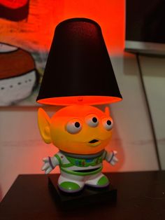 a lamp that is sitting on top of a table with a small toy in front of it