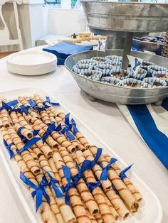 an assortment of desserts are displayed on a table with blue ribbons and plates in the background