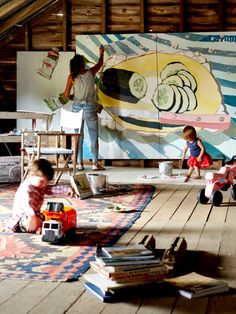 two children are playing on the floor in front of a large painting with people working on it