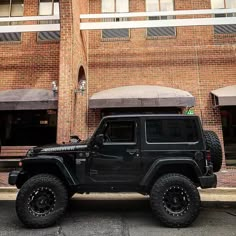 a black jeep parked in front of a brick building