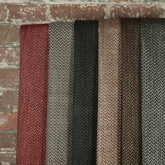 four different colors of knitted fabric hanging on a brick wall next to a window