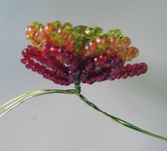 a flower made out of beads sitting on top of a white table next to a wall