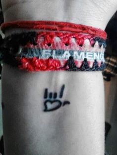 a person wearing a red and black bracelet with the word pinterest on it