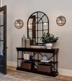 an entryway with a mirror, shelf and vase on the floor next to it