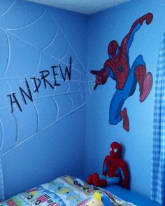 a child's bedroom decorated in blue and red with spiderman on the wall