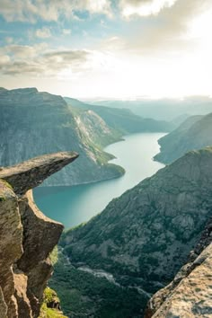 a person standing on the edge of a cliff overlooking a body of water and mountains