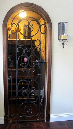 an ornate iron door in the corner of a room with wood floors and tile flooring