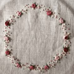 a white and pink flowered necklace with pearls on it's end is laying on top of a piece of cloth