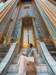 a woman sitting on steps in front of an ornate building with blue and gold tiles