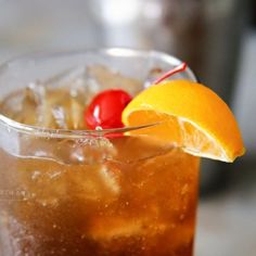 a close up of a drink with an orange slice and cherries on the rim