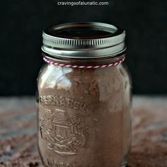 a mason jar filled with brown liquid sitting on top of a carpeted floor next to a black wall