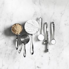 various kitchen utensils and spoons on a marble countertop with white background