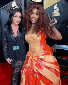 two women standing next to each other on a red carpet