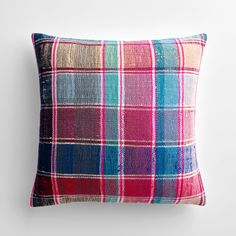 a colorful plaid pillow on a white wall