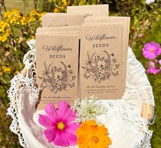 three seed packets sitting on top of a white doily with pink and yellow flowers