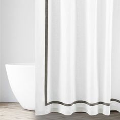 a white shower curtain with black trim on the bottom and grey line around the edge