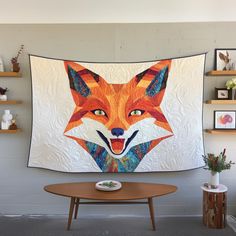 a quilt hanging on the wall next to a table