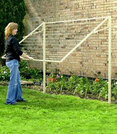 a woman standing in front of a brick building with a soccer goal on the grass