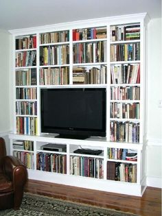 a living room with a large bookcase filled with books and a flat screen tv