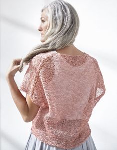 a woman with grey hair wearing a pink top