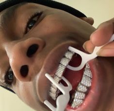 a young man is brushing his teeth with braces on top of his head and holding a toothbrush in front of his mouth