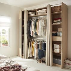 an open closet with clothes hanging on the shelves and other items in front of it