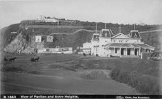 an old black and white photo of a house on the side of a hill with horses standing in front of it